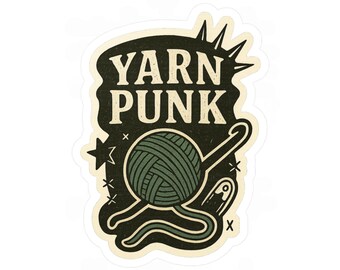 Op de afbeelding: Een sticker met de tekst "YARN PUNK" in een vintage lettertype. Het ontwerp toont een groene bol wol, een haaknaald en een veiligheidsspeld. De achtergrond is donkergroen met ster- en kruisaccenten.