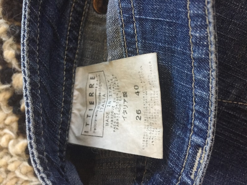 May include: A blue denim jean label with white text that reads "ITTIERRE", "Pettoranello di Molise", "ITALIA", "MADE IN ITALY", "PARRICUP EN ITALTE", "FABRICADO EN ITAL", "PAIS OF ORIGENLEICA", "ITALIA", "26", "40".
