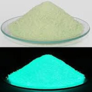 May include: A pile of bright green glow-in-the-dark powder. The powder is illuminated by a blacklight, showing its vibrant green glow.