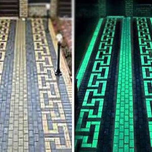 Puede incluir: Un camino de entrada hecho de adoquines de hormigón con un patrón geométrico. Los adoquines brillan en la oscuridad, creando un efecto luminoso.