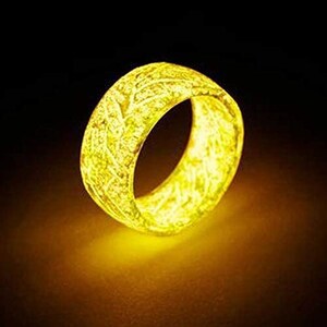 Op de afbeelding: Een glimmende gele ring met een getextureerd oppervlak. De ring is gemaakt van hars en heeft een uniek ontwerp.