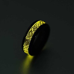 Op de afbeelding: Een zwarte ring met een gloeiende gele band met een Keltisch knoopontwerp.