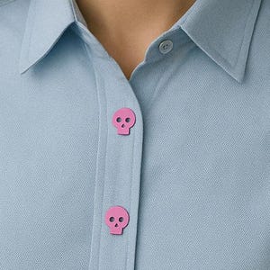 May include: A light blue button-down shirt with pink skull buttons.