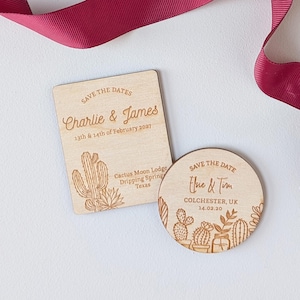 May include: Two wooden save-the-date announcements. One is rectangular with the text "Charlie & James" and "13th & 14th of February 2027". The other is round with the text "Elsie & Tim" and "14.02.20". Both feature cactus illustrations.