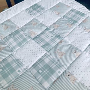 May include: A patchwork quilt featuring a repeating pattern of sage green and white squares. The design includes alternating blocks of sage green and white stripes, sage green plaid with white stars, white fabric with tiny dots, and teddy bears.