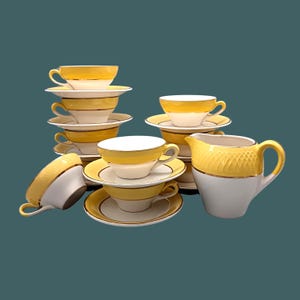 Peut inclure: Un ensemble de tasses à thé et de soucoupes jaunes et blanches avec des bordures dorées. L'ensemble comprend un pot à crème.