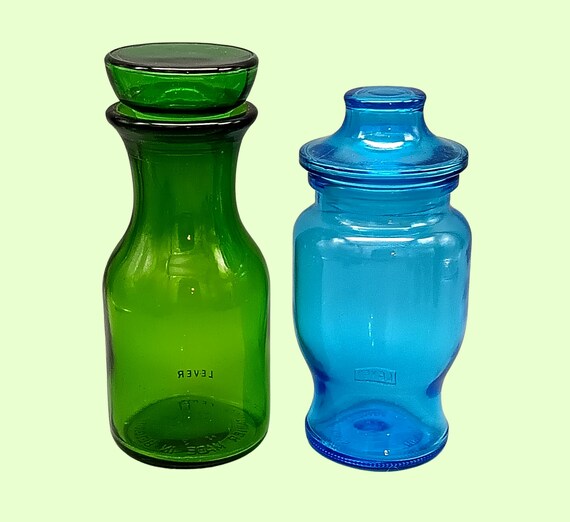 Pair of turquoise blue and emerald green glass POTs, jars with airtight pagoda caps, lever