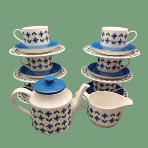 Könnte beinhalten: Ein Vintage-Tee-Set mit einem blauen und weißen Blumenmuster. Das Set enthält eine Teekanne, eine Milchkännchen und vier Tassen und Untertassen.
