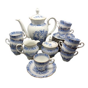 May include: A blue and white porcelain tea set with gold accents. The set includes a teapot, creamer, sugar bowl, and six cups and saucers.