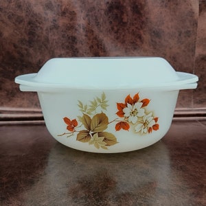 May include: White ceramic casserole dish with a floral design featuring brown and orange leaves and white flowers. The dish has a lid.