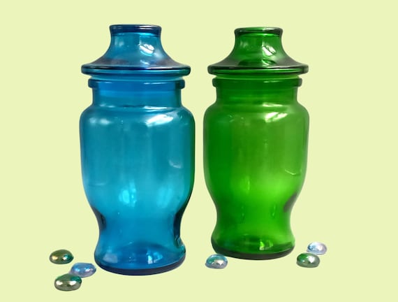 Pair of turquoise blue and emerald green glass POTs, jars with airtight pagoda caps, lever