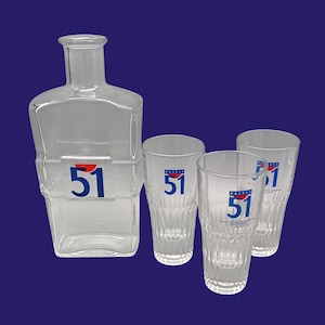 Puede incluir: Un juego de tres vasos de chupito de vidrio transparente con el texto "Pastis 51" impreso en ellos. También se incluye una jarra de vidrio transparente con el número "51" impreso en ella.