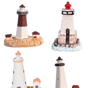 May include: Set of four miniature lighthouse figurines. Each lighthouse is made of white painted resin and features a red, brown, or black roof. The lighthouses are set on a base of sand or water.