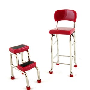 May include: A miniature red and chrome step stool and bar stool set. The step stool has two black steps and red feet. The bar stool has a red seat and back, with chrome legs and red feet. The set is on a white background.