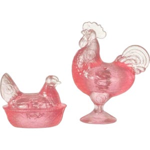 May include: Two pink glass chicken figurines. One is a rooster with a detailed comb and tail. The other is a hen sitting in a nest. Both are transparent and have a vintage aesthetic.