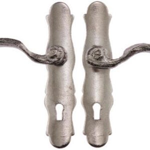 May include: A pair of antique-style door handles in a silver finish. Each handle features a curved lever and ornate detailing around the base and keyhole. The handles are designed for a classic or vintage aesthetic.