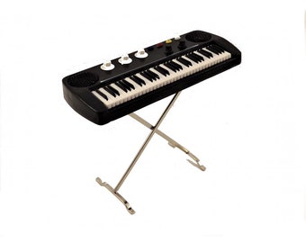 May include: A black keyboard with a silver stand. The keyboard has 61 keys and a few knobs on the top.