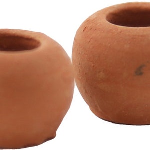 May include: Two small, round, terracotta-colored candle holders. Each has a circular opening at the top and a smooth, unglazed surface. The candle holders are ideal for small candles or tea lights and add a rustic touch to any decor.