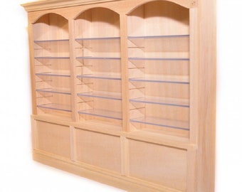 Puede incluir: Una estantería de madera con tres secciones, cada una con tapas arqueadas y múltiples estantes. Los estantes son de acrílico transparente y la estantería está sin terminar.