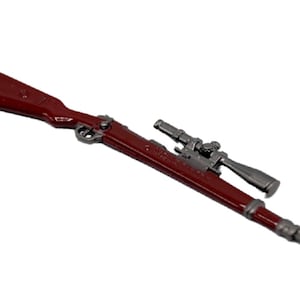 Puede incluir: Un rifle de juguete de metal rojo con una mira telescópica plateada. El rifle tiene un diseño detallado y es un gran objeto de colección.