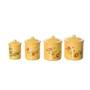 May include: Four yellow ceramic canisters with lids. Each canister is decorated with a floral pattern in red, green, and yellow. The canisters are of varying sizes, with the smallest on the left and the largest on the right.