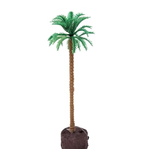 May include: A small plastic palm tree with a brown trunk and green leaves. The tree is sitting on a brown base.