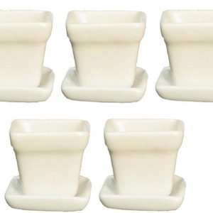 May include: Set of five white ceramic square plant pots with matching saucers. The pots are approximately 3 inches tall and 3 inches wide.