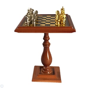 May include: A wooden chess table with a brown finish. The table has a square top with a black and white checkered chessboard. The chessboard has silver and gold chess pieces set up for a game. The table has a pedestal base with a fluted design.