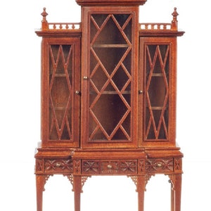 May include: A wooden cabinet with a pagoda-style top and glass doors. The cabinet has three shelves and a drawer. The cabinet is made of a dark wood with a reddish hue.