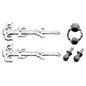 May include: A collection of silver-finished, antique-style door hardware. The set comprises two decorative hinges, a door knocker with a ring, and two small knobs. The hardware has a distressed look, giving it a vintage or aged appearance.