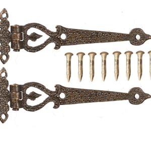 Op de afbeelding: Twee sierlijke zwarte metalen scharnieren met decoratieve krulwerk en een gehammerde afwerking. De scharnieren zijn bevestigd op een witte achtergrond en worden geleverd met 12 goudkleurige spijkers.