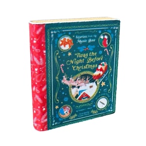 May include: A small book titled "Twas the Night Before Christmas" with a teal cover and red spine. The cover features illustrations of Santa's sleigh, candy canes, and a Christmas stocking. The spine has a repeating pattern of white snowflakes.