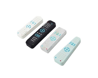 May include: Four miniature remote controls in different colors: white, black, silver, and light blue. Each remote has a circular button with a blue design.