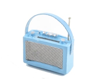 May include: A light blue vintage-style radio with a carrying handle and a telescoping antenna. The radio has a speaker grille with a hexagonal pattern.