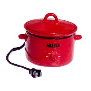 以下が含まれることがあります： 黒のコードとプラグが付いた赤いスロークッカー。スロークッカーには黒いノブがあり、前面に「AUTO」と印刷されています。