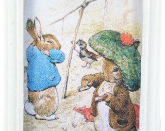 Könnte beinhalten: Eine gerahmte Illustration von zwei Kaninchen, eines in einer blauen Jacke und das andere in einem grünen Hut, mit einem kleinen Vogel im Hintergrund.