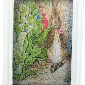 Könnte beinhalten: Eine gerahmte Illustration eines Kaninchens, das eine braune Jacke trägt und eine rote Blume hält. Das Kaninchen steht in einem Garten mit grünen Pflanzen und einem braunen Hintergrund.