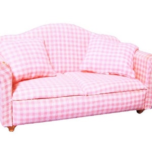 May include: A pink and white gingham patterned sofa with two pillows. The sofa has a curved back and wooden legs.