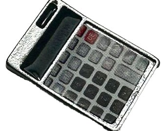 May include: A silver calculator with a black display and black buttons. The calculator has a textured surface.
