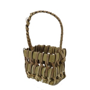May include: A small, woven basket with a handle made of natural brown and tan materials. The basket is rectangular and has a woven pattern.