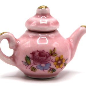 Könnte beinhalten: Eine kleine rosa Teekanne mit Blumenmuster. Die Teekanne hat einen Deckel und einen Henkel. Die Teekanne ist aus Keramik.