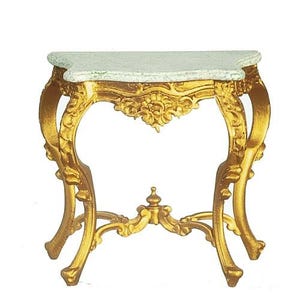 May include: A gold-colored console table featuring ornate, curved legs and a central decorative element. The tabletop has a light-colored, speckled surface with a semi-circular shape. The frame is detailed with intricate carvings throughout the structure.