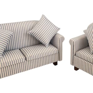 May include: A miniature living room set comprising a striped sofa and armchair. The furniture is upholstered in a cream fabric with grey vertical stripes. Each piece has a matching striped cushion. The set has dark brown wooden legs.