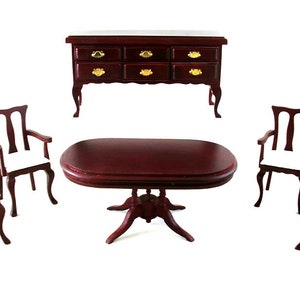 Puede incluir: Un juego de comedor de caoba con una mesa redonda y cuatro sillas. Las sillas tienen cojines blancos y la mesa tiene una base de pedestal.