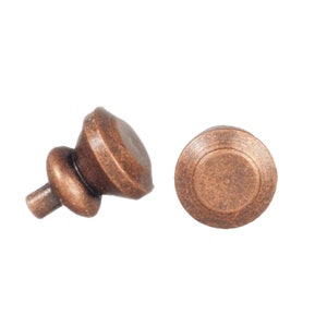 Op de afbeelding: Twee antieke koperen kastknoppen. Eén knop is rond en de andere is van een traditioneler ontwerp met een afgeronde bovenkant en een kleine steel.