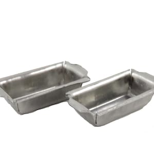 Puede incluir: Dos moldes para pan de plata, hechos de metal, se muestran sobre un fondo blanco. Los moldes son de forma rectangular y tienen un fondo ligeramente redondeado.