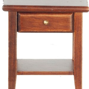 Può includere: Un tavolino da comodino in legno marrone scuro con un cassetto e uno scaffale inferiore. Il cassetto ha una maniglia in ottone.