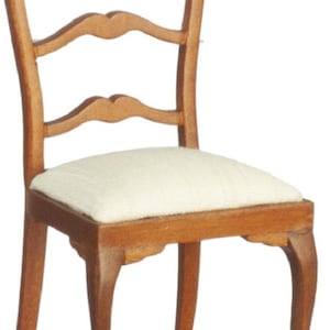 May include: A miniature wooden chair with a light-colored seat cushion. The chair has a curved back with three decorative cutouts and elegantly curved legs. The wood has a warm, natural finish, suggesting a classic or antique style.