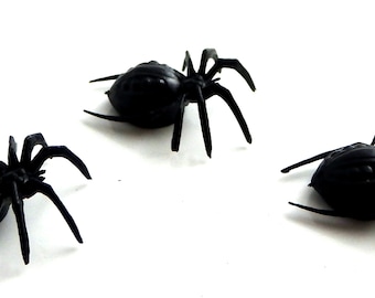 May include: Three black plastic spiders with eight legs and a textured body.