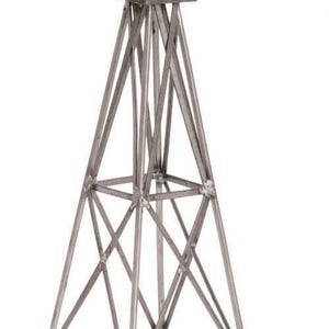 Puede incluir: Una escultura de molino de viento de metal con acabado plateado y detalles rojos en las aspas. El molino de viento presenta un diseño detallado con una torre alta de estructura abierta. Es un objeto decorativo.